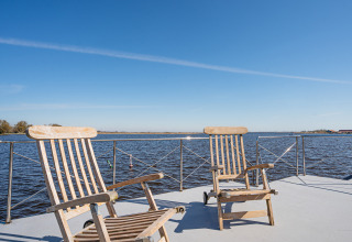 Due sedie di legno sul ponte della houseboat Campi a Marina Uitgeest, Paesi Bassi, con vista sull’acqua.