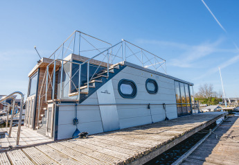 Das moderne Hausboot „Campi“ liegt bei sonnigem Wetter im Yachthafen Uitgeest in den Niederlanden.