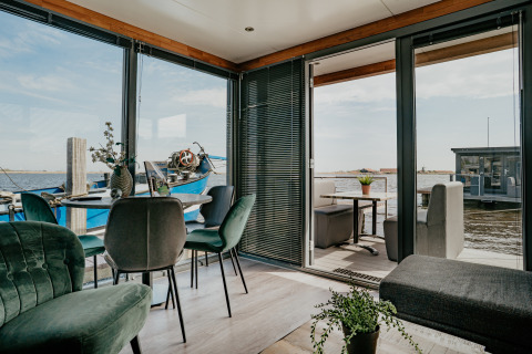 Interior moderno de Houseboat Havenlodge con paredes de vidrio, vistas al agua y terraza soleada.