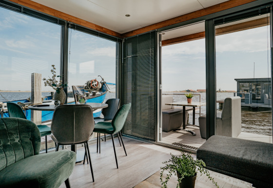 Modernes Wohnzimmer auf dem Hausboot Havenlodge mit Blick auf das Wasser, Terrasse und Boot.