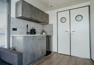 Cocineta moderna con gabinetes grises y puertas dobles en Houseboat «Havenlodge» en Marina Uitgeest, Países Bajos.