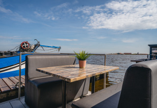 Outdoor seating with table and plant on Houseboat Havenlodge at Marina Uitgeest, Netherlands, water view.