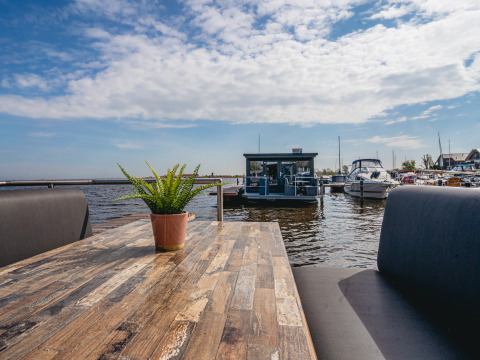 Vista desde una mesa en la casa flotante Havenlodge en Marina Uitgeest, con barcos y cielo al fondo.