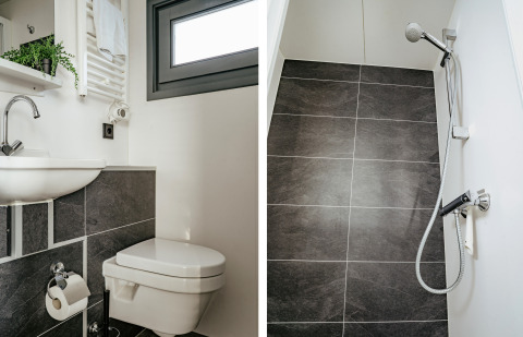 Baño y ducha modernos con baldosas oscuras en el suelo en la casa flotante Havenlodge en Marina Uitgeest, Países Bajos.