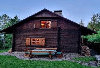 Foto einer gemütlichen Holzhütte namens Schneiderhütte mit Gartensitzgruppe im Wald in Österreich.