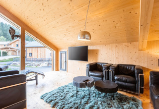 Lichte woonkamer in Kreischberg Chalets 28, Oostenrijk, met houten interieur, leren stoelen en grote ramen.