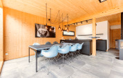 Salle à manger moderne de chalet avec chaises bleues, table noire, murs en bois et lampes stylées en Autriche.