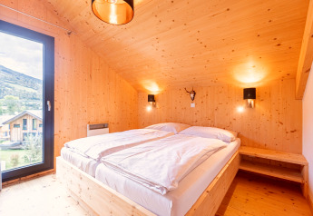 Chambre du Kreischberg Chalets 28 en Autriche, intérieur bois, lit double, vue sur la montagne.