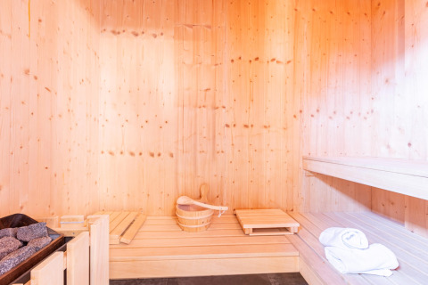 Licht houten sauna-interieur met emmer, saunastenen, zitbanken en handdoeken, Kreischberg Chalets 28.