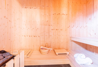 Licht houten sauna-interieur met emmer, saunastenen, zitbanken en handdoeken, Kreischberg Chalets 28.