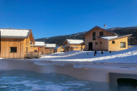Uitzicht op met sneeuw bedekte houten chalets en bergen bij Kreischberg Chalets 28 op een heldere winterdag in Oostenrijk.