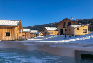 Uitzicht op met sneeuw bedekte houten chalets en bergen bij Kreischberg Chalets 28 op een heldere winterdag in Oostenrijk.