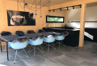 Moderne eetkamer en keuken in Kreischberg Chalets 28 in Oostenrijk met blauwe stoelen en houten muren.