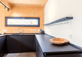 Cuisine moderne du Kreischberg Chalets 28 en Autriche, avec armoires noires et verres suspendus.
