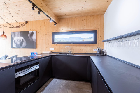 Moderne keuken met zwarte kastjes en houten muren in Kreischberg Chalets 28, Oostenrijk, met uitzicht.