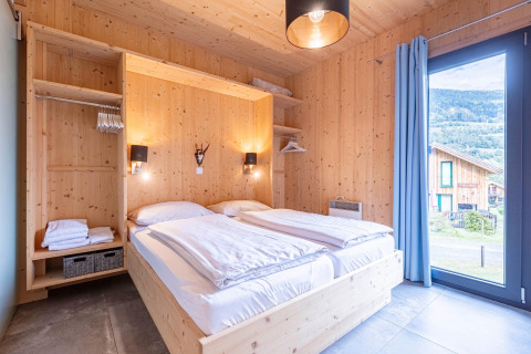 Slaapkamer in Kreischberg Chalets 28, Oostenrijk met houten interieur, tweepersoonsbed en groot raam.