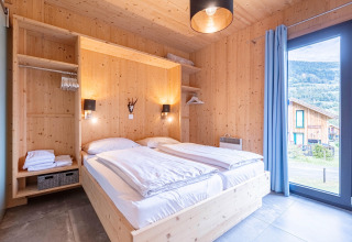 Slaapkamer in Kreischberg Chalets 28, Oostenrijk met houten interieur, tweepersoonsbed en groot raam.