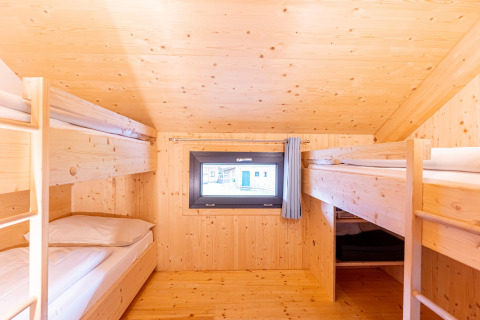 Slaapkamer met houten stapelbedden en klein raam in Kreischberg Chalets 28 in Oostenrijk.