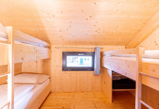 Slaapkamer met houten stapelbedden en klein raam in Kreischberg Chalets 28 in Oostenrijk.