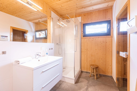 Moderne houten badkamer bij Kreischberg Chalets 28 in Oostenrijk met douche, wastafel en krukje.