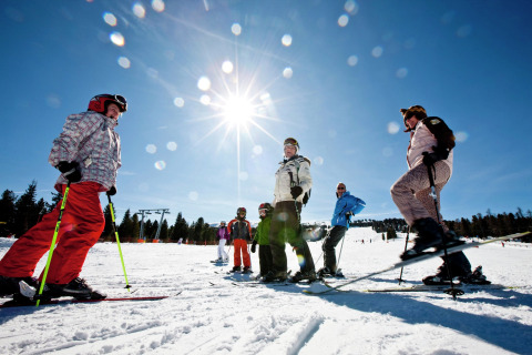 Groep skiërs geniet van zonnige winterdag bij Kreischberg Chalets 28 in Oostenrijk onder blauwe hemel.