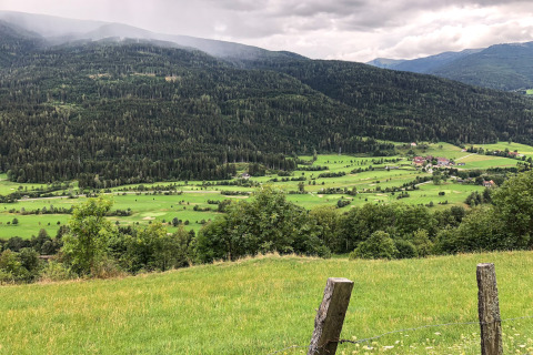 Uitzicht op groene heuvels en een dal vanaf Kreischberg Chalets 28 in Oostenrijk onder een bewolkte lucht.