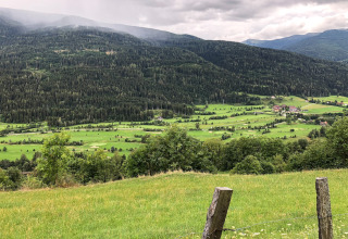 Uitzicht op groene heuvels en een dal vanaf Kreischberg Chalets 28 in Oostenrijk onder een bewolkte lucht.