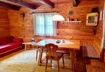 Træbeklædt spisestue i Schneiderhütte, Østrig, med rustik indretning og varme, hyggelige farver.