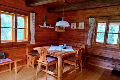 Gemütliche Essecke aus Holz mit Fenstern, Holzmöbeln und Dekor in der Schneiderhütte in Österreich.