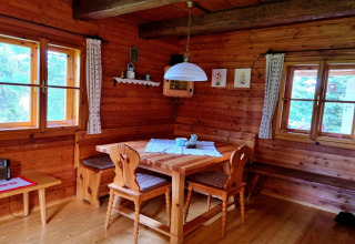Gemütliche Essecke aus Holz mit Fenstern, Holzmöbeln und Dekor in der Schneiderhütte in Österreich.