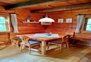 Accogliente angolo pranzo con pareti in legno e sedie rustiche presso lo chalet Schneiderhütte, Austria.