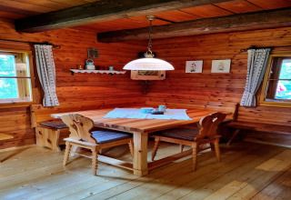 Gemütliche Stube mit Holzwänden, Eckbank und handgefertigten Stühlen in der Schneiderhütte, Österreich.