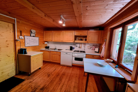 Holzverkleidete Küche in der Schneiderhütte in Österreich mit Fensterblick, Herd und warmem Flair.