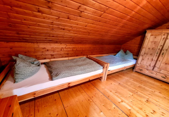 Træbeklædt værelse i chalet Schneiderhütte, Østrig, med to enkeltsenge og et garderobeskab.