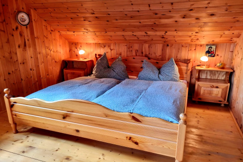 Camera da letto nello chalet Schneiderhütte in Austria con pareti in legno, letto matrimoniale e comodini.