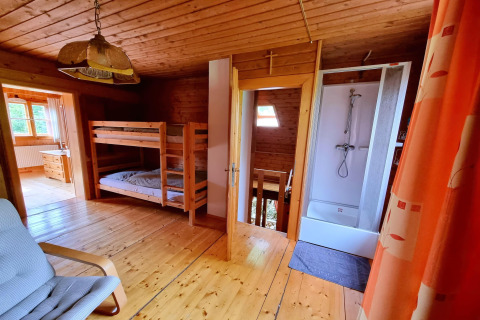 Innenaufnahme des Schneiderhütte-Chalets in Österreich mit Etagenbetten, Dusche und Holzinterieur.