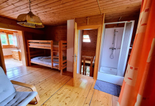 Innenaufnahme des Schneiderhütte-Chalets in Österreich mit Etagenbetten, Dusche und Holzinterieur.