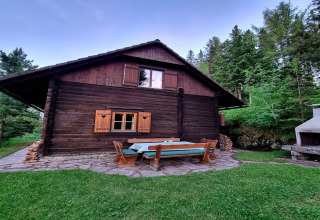 Das Schneiderhütte Chalet in Österreich mit Sitzbereich im Freien, umgeben von Bäumen und Wald.