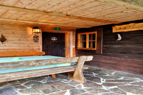 Area esterna dello chalet Schneiderhütte in Austria con panca di legno, tavolo e terrazza in pietra.