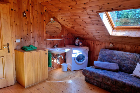 Holzgetäfeltes Zimmer im Schneiderhütte-Chalet mit Waschbecken, Waschmaschine und Sofa in Österreich.