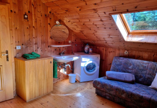 Holzgetäfeltes Zimmer im Schneiderhütte-Chalet mit Waschbecken, Waschmaschine und Sofa in Österreich.