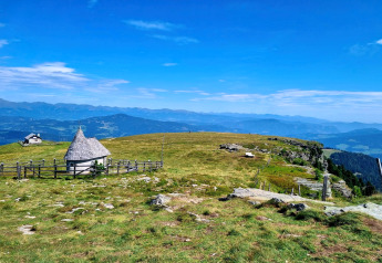 Alpeudsigt ved Schneiderhütte i Østrig med grønne marker, bjergtoppe og en lille charmerende bygning.