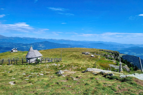 Berglandschaft bei der Schneiderhütte in Österreich mit grünen Wiesen, Hütten und weitem Alpenblick.