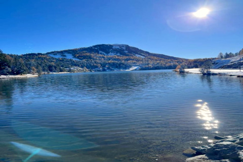 Vista di un lago tranquillo con montagne innevate e cielo limpido, vicino a Schneiderhütte in Austria.