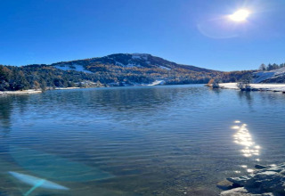 Vista di un lago tranquillo con montagne innevate e cielo limpido, vicino a Schneiderhütte in Austria.