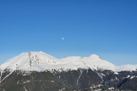 Aussicht von der Schneiderhütte in Österreich mit schneebedeckten Bergen und sichtbarem Mond am Himmel.