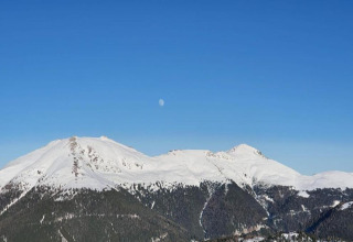 Aussicht von der Schneiderhütte in Österreich mit schneebedeckten Bergen und sichtbarem Mond am Himmel.