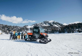 Gruppe Skifahrer und Schneemobil vor der Schneiderhütte im verschneiten Berggebiet in Österreich.