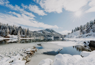 Snowy alpine landscape near a lake at Alpenpark Turrach 21, Austria, under a bright sunny winter sky.