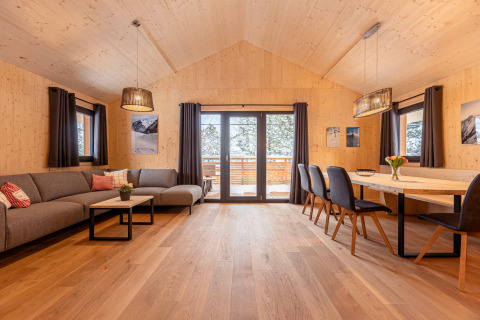 Ruime woonkamer en eetruimte met houtdecor in Nature chalets Turracher Höhe 1, Oostenrijk, met grote ramen.